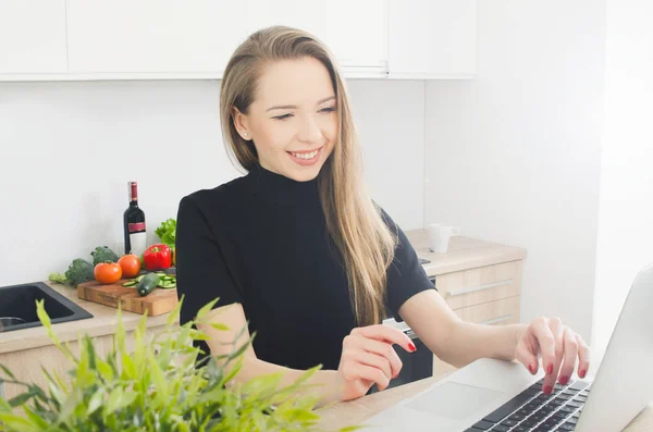 Mosolygó fiatal nő laptop a konyhában — Stock Fotó