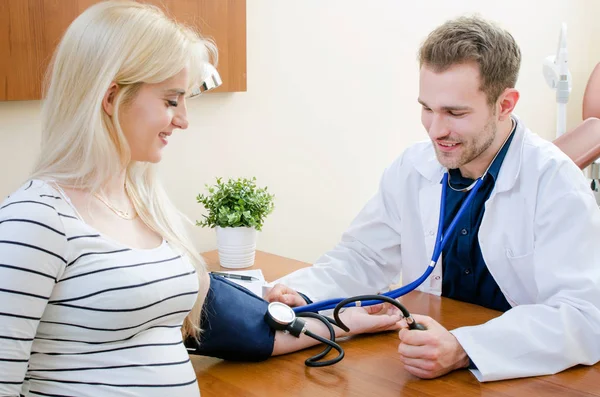 Médico joven comprobando la presión arterial del paciente femenino — Foto de Stock