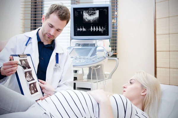 Médico mostrando imagem de ultra-som do bebê para mulher grávida . — Fotografia de Stock