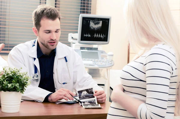 Doctor showing baby ultrasound image to pregnant woman — Stock Photo, Image