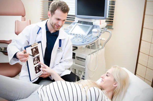 Doctor showing baby ultrasound image to pregnant woman — Stock Photo, Image