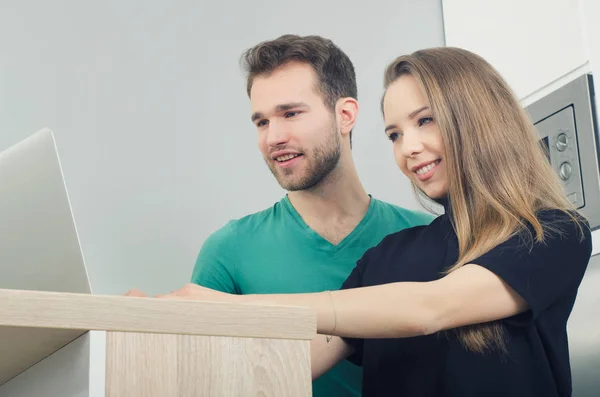 Couple uses the computer in the kitchen — Stock Photo, Image