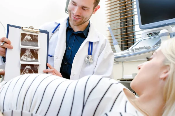 Médico mostrando imagen de ultrasonido de bebé a mujer embarazada — Foto de Stock