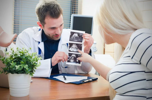 Doctor showing baby ultrasound image to pregnant woman — Stock Photo, Image