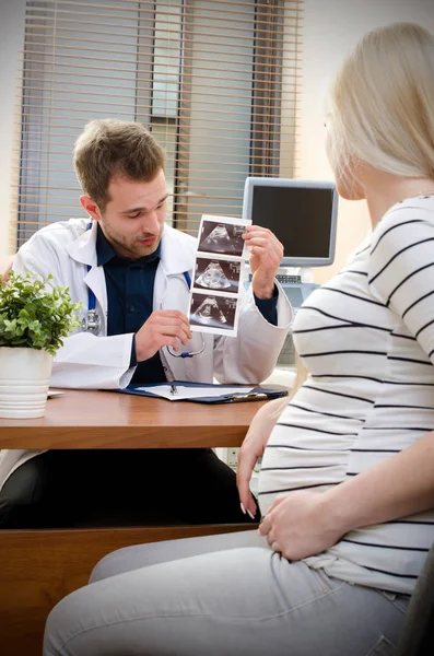 Médico mostrando imagen de ultrasonido de bebé a mujer embarazada — Foto de Stock