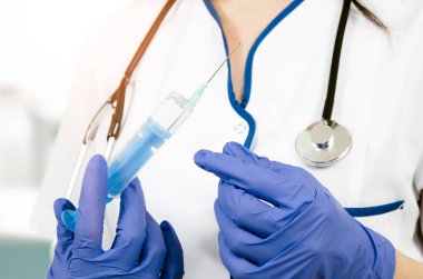 Kadın doktor eldivenli tıbbi enjeksiyon şırınga tutarak