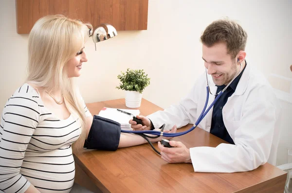 Médico joven comprobando la presión arterial del paciente femenino — Foto de Stock