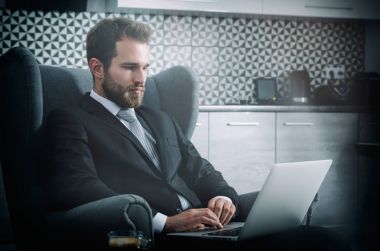 Dizüstü bilgisayar ile evden çalışan genç iş adamı