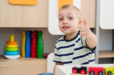 Masada oturan ve jest yukarı gösteren mutlu çocuk