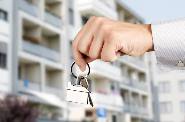 Homem mão segurando chaves com a nova casa — Fotografia de Stock