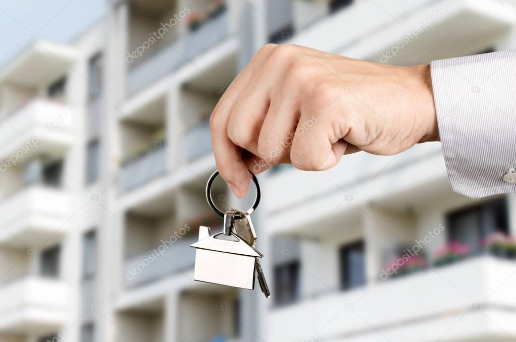 Man hand holding keys with to new house