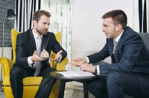 Real estate agent discussing with blueprints and house model — Stock Photo, Image