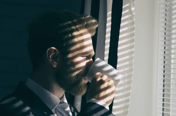 Handsome young bearded businessman is looking out the window — Stock Photo, Image