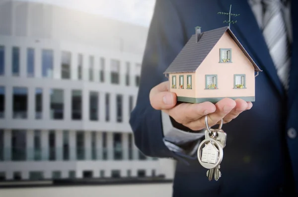 Real estate agent with home keys and house miniature — Stock Photo, Image