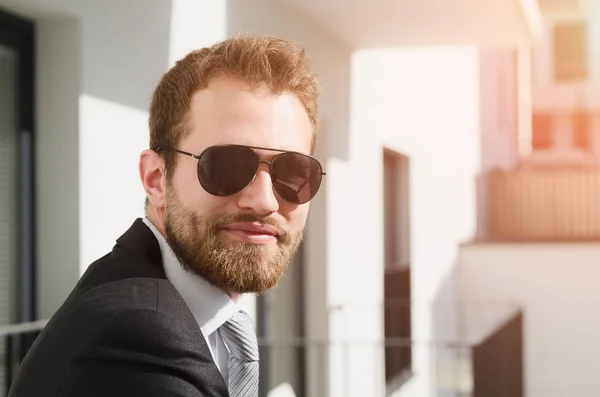 Handsome businessman in sunglasses standing on the balcony — Stock Photo, Image