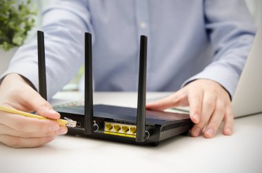 Adam Ethernet kablosu yönlendiriciye takılan.