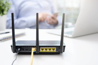 Kablosuz yönlendirici ve evde bir akıllı telefon kullanan adam