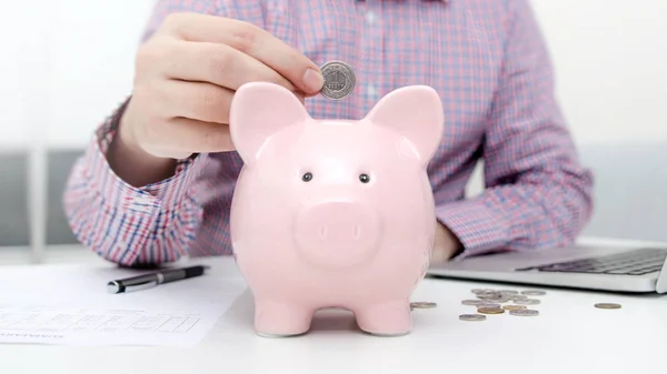 Hombre poniendo moneda en alcancía — Foto de Stock