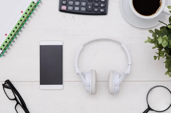 Office desk table layout with headphones and smartphone