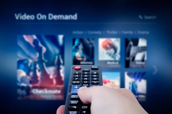 VOD service screen with remote control in hand — Stock Photo, Image