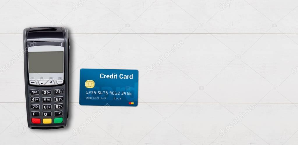 Payment terminal and credit card on wooden background