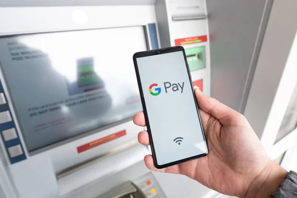 Чоловік тримає смартфон з логотипом Google Pay — стокове фото