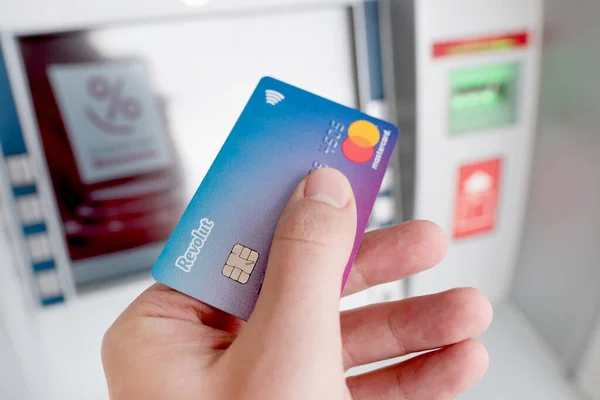 Revolut debit card in hand, ATM in background — Stock Photo, Image