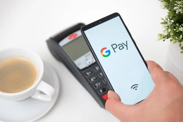 Чоловік тримає смартфон з логотипом Google Pay — стокове фото