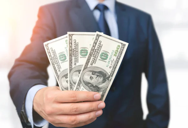 Een man in een pak heeft bankbiljetten van honderd dollar. — Stockfoto