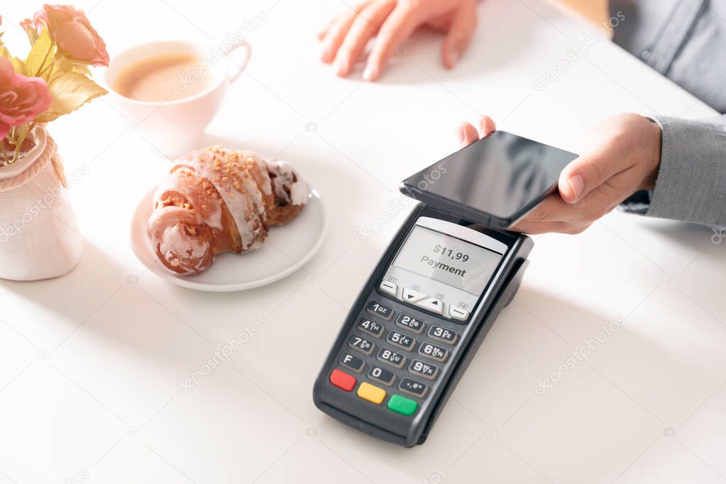 Man using smart phone to pay in restaurant