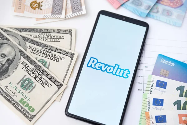 Logo della banca Revolut sullo schermo del telefono e sulle valute — Foto Stock