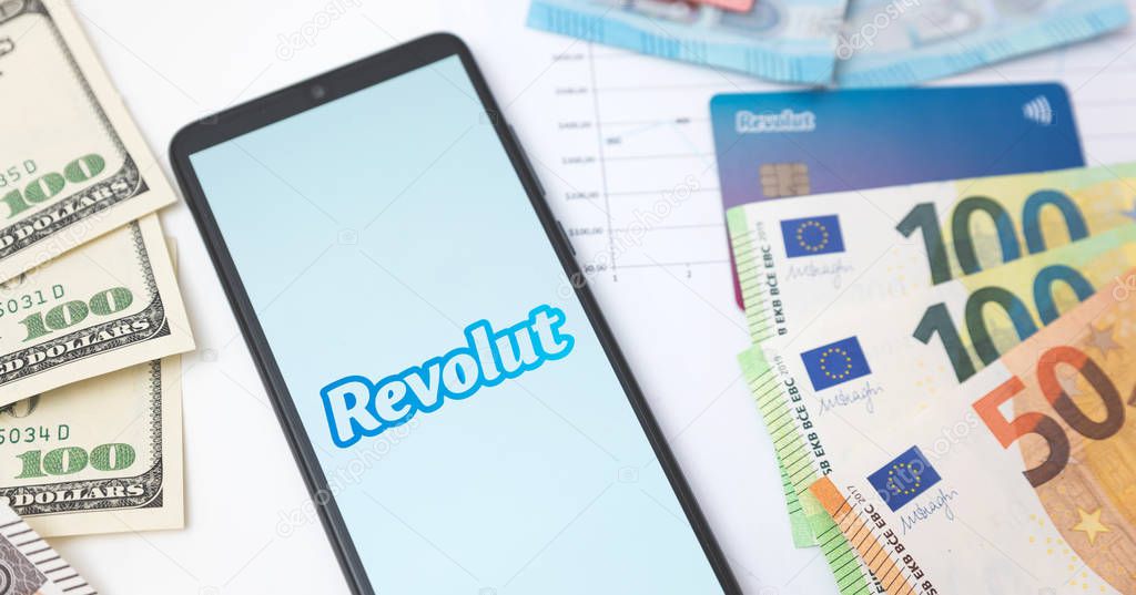 Wroclaw, Poland - NOV 06, 2019: Revolut bank logo on the smartphone screen next to banknotes. Revolut Ltd is a UK financial technology company that offers banking services.