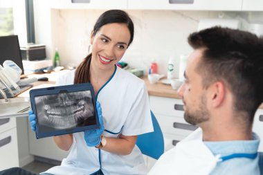 Female dentist showing teeth x-ray on tablet clipart