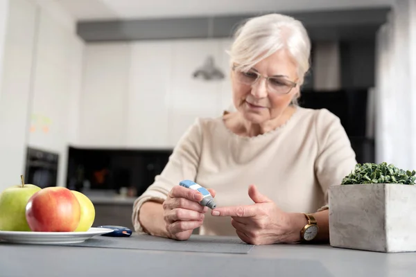 Старшая женщина проверяет уровень глюкозы в крови — стоковое фото
