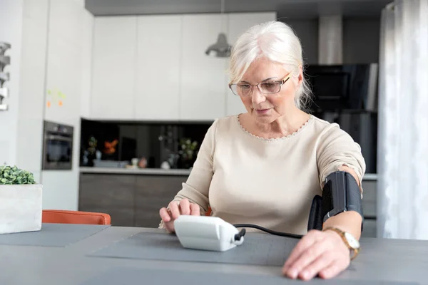 Mulher adulta sênior medindo a pressão arterial — Fotografia de Stock