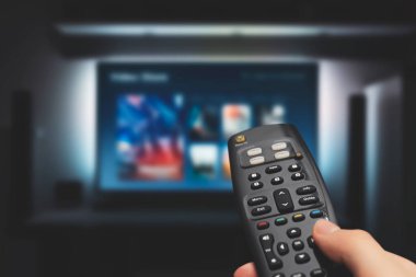 Televizyondaki Vod servisi. TV izleyen adam, canlı yayın servisi, talep üzerine video, uzaktan kumanda.