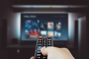 Televizyondaki Vod servisi. TV izleyen adam, canlı yayın servisi, talep üzerine video, uzaktan kumanda.