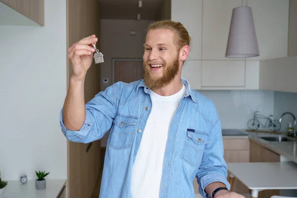 Happy young man renter first time home owner holding key to new apartment