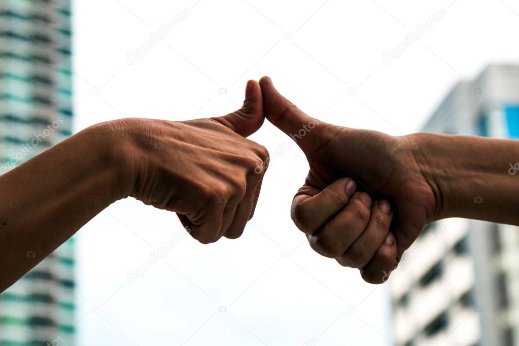 silhouette of Two men expressing thumb finger and touching together for good corporation