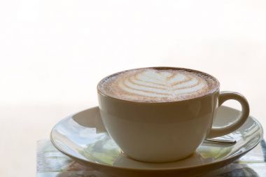 Kahve sanat latte üzerinde açık üzerinden sıcak ışık parlama ile beyaz, vintage kahve fincan