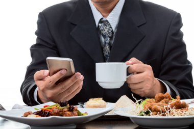 Cep telefonu haberleri kontrol ve beyaz arka plan üzerinde kahvaltı yemek yerken kahve fincanı alarak iş adamı