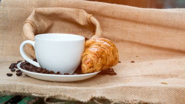 Kruvasan ve masanın üzerine fasulye ile kahve fincanı