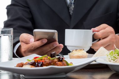 Beyaz arka plan üzerinde eatting kahvaltı sırasında cep telefonu haberleri kontrol işadamı yakın çekim