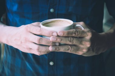 Sıcak latte fincan kahve onun elinde tutan adam