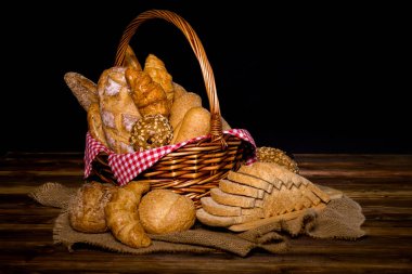 Kümesiyle pişmiş ekmek sepeti; Susam çörek, baget, pişmiş rulo, kruvasan, yuvarlak topuz ve bütün tahıl gibi çeşitli taze ekmek ekmek dilimlenmiş