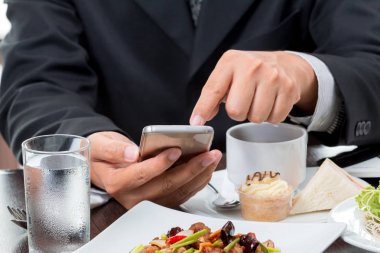 Beyaz arka plan üzerinde eatting kahvaltı sırasında cep telefonu haberleri kontrol işadamı yakın çekim