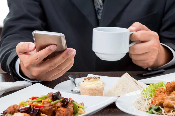 Cep telefonu haberleri kontrol ve beyaz arka plan üzerinde eatting kahvaltı sırasında kahve fincanı alarak işadamı yakın çekim