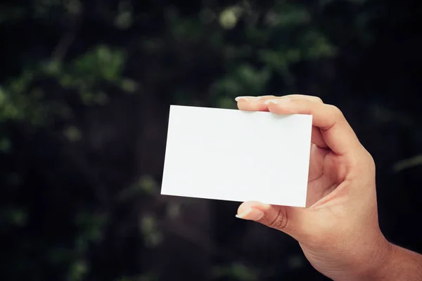 Woman\'s hand showing business card - closeup shot on nature background