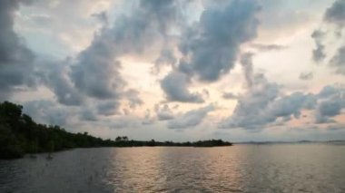 Mangrov ormanı ve denizin yakınlarında bir çok bulut hareketiyle güneşin doğuşu zaman aşımı