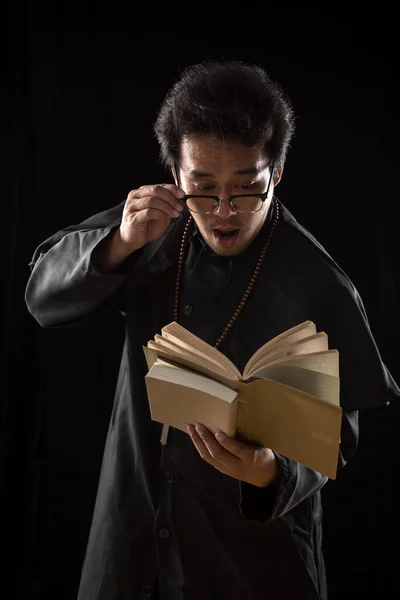 Молодой Священник Ловит Очки Паникует Глядя Старую Библию Черном Фоне — стоковое фото